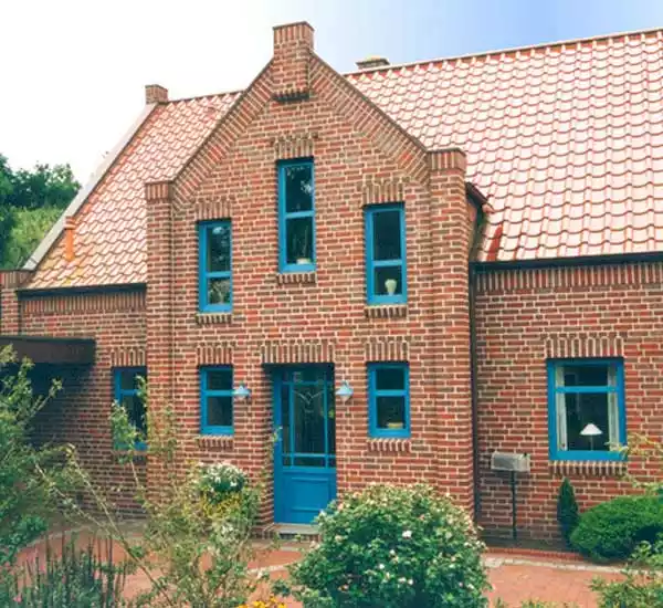 Haus mit roten Klinkern und blauen Fenstern und Haustür mit Drehkippfenstern